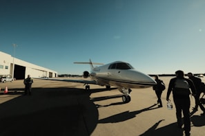 An entourage of impeccably dressed individuals walking confidently beside a grand private jet, illustrating the sovereign-level experience of Travuxe Legacy.