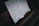 A close-up view of a piano keyboard with an open sheet of classical music. The sheet music rests on top of the piano, showing notes and musical notations in detail. The lighting creates a slightly moody and intimate atmosphere, with shadows enhancing the texture of the wood and keys.