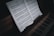A close-up view of a piano keyboard with an open sheet of classical music. The sheet music rests on top of the piano, showing notes and musical notations in detail. The lighting creates a slightly moody and intimate atmosphere, with shadows enhancing the texture of the wood and keys.