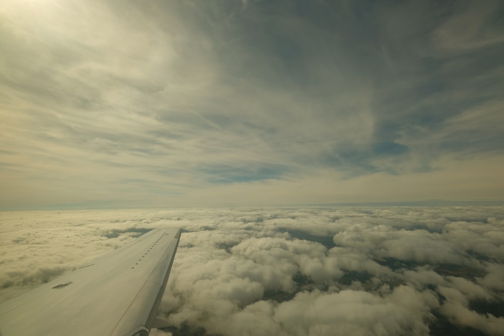 a view of the wing of a plane flying above the clouds