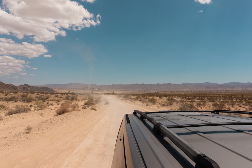 a truck driving down a dirt road in the desert