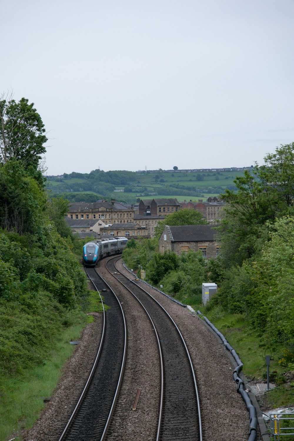 a train traveling down train tracks next to a lush green hillside