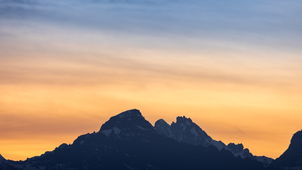 a plane flying over a mountain range at sunset