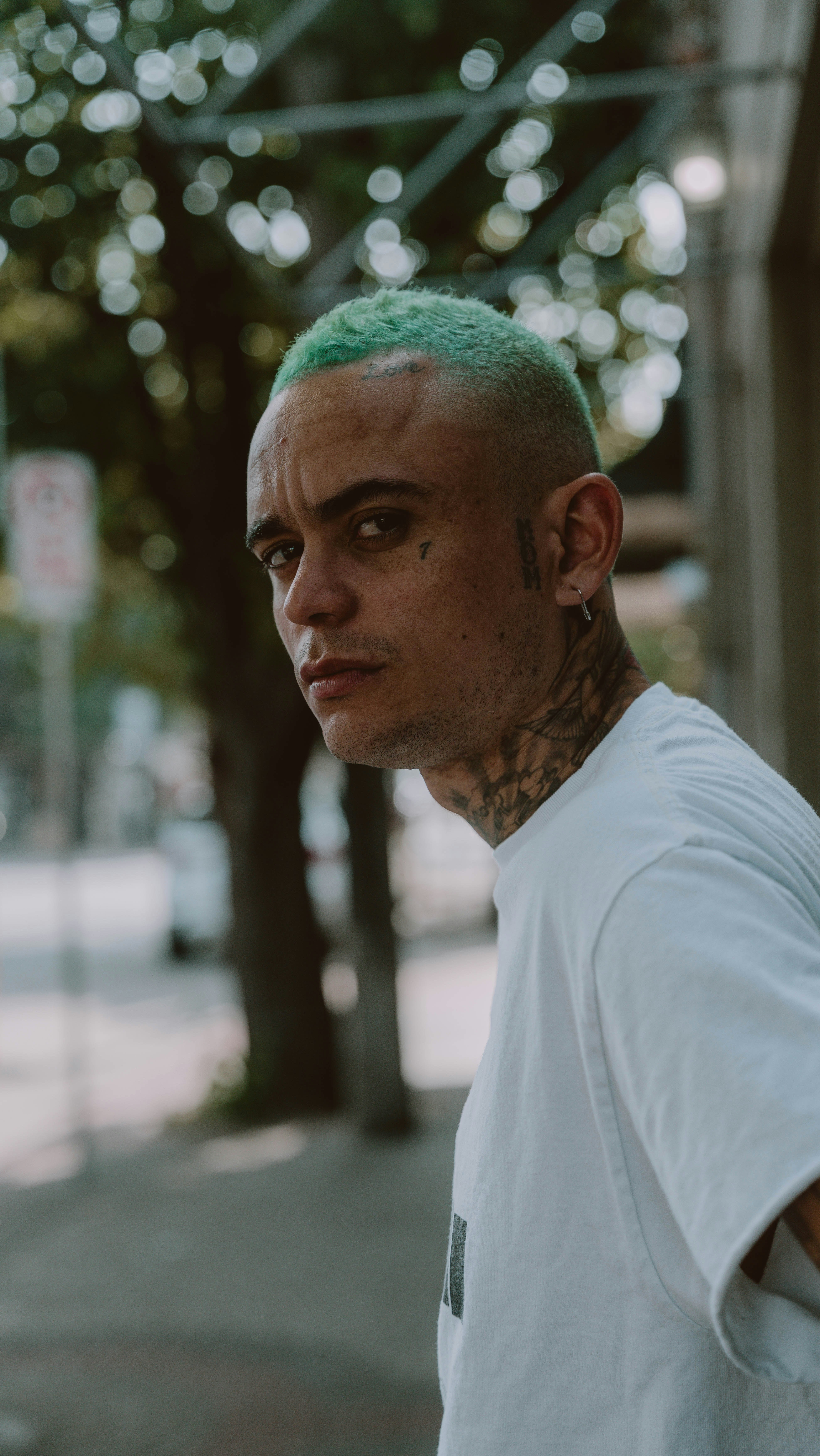 Un hombre con cabello verde y piercings en la cabeza