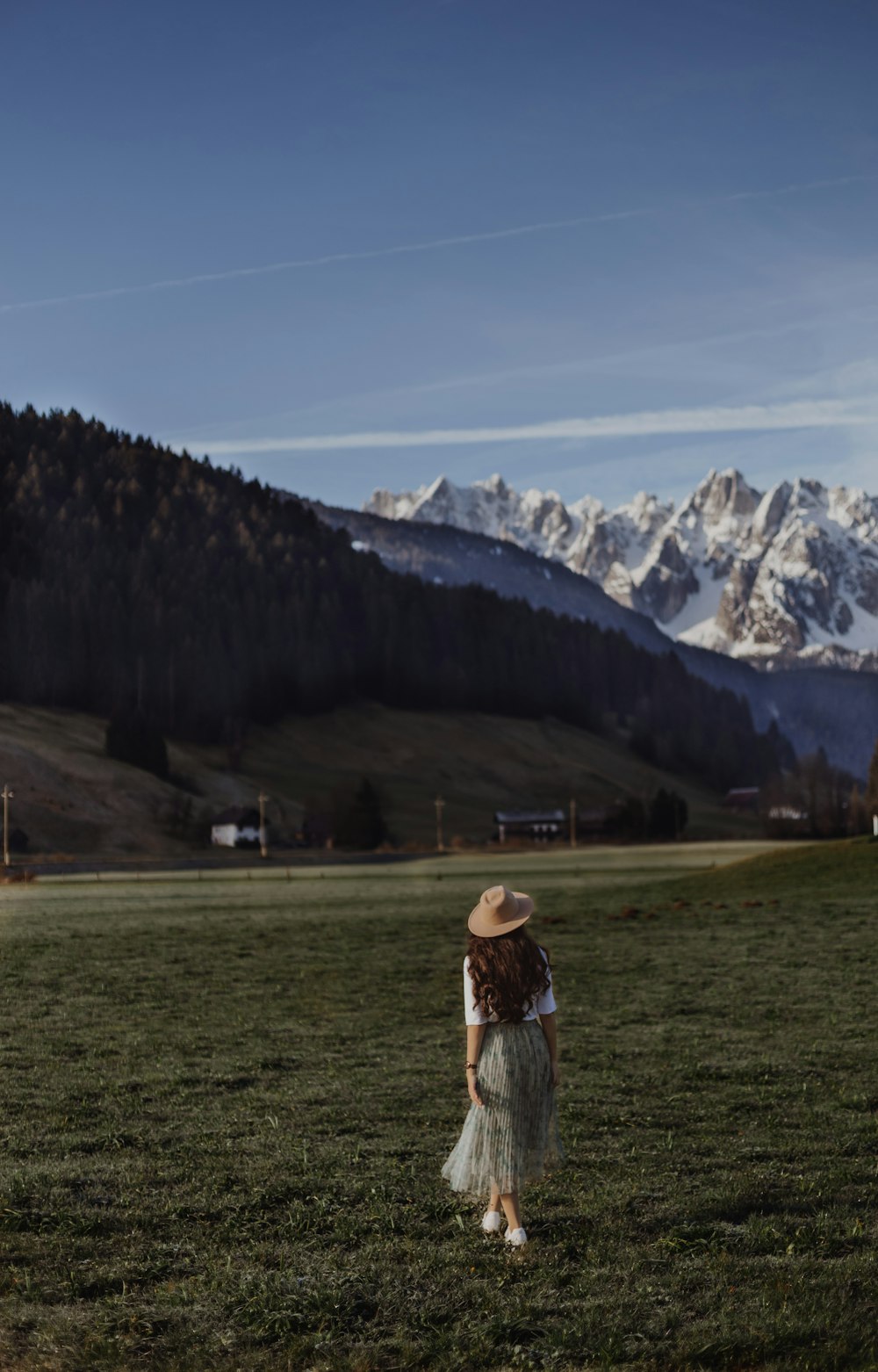 a woman standing in a field with mountains in the background