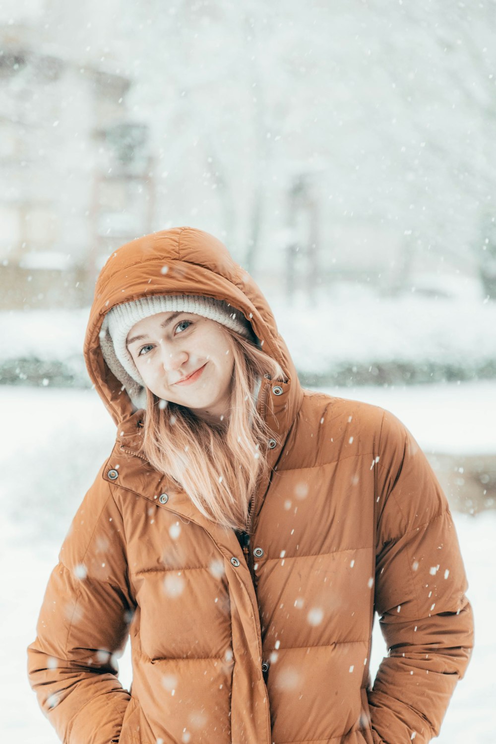 a woman standing in the snow wearing a brown jacket