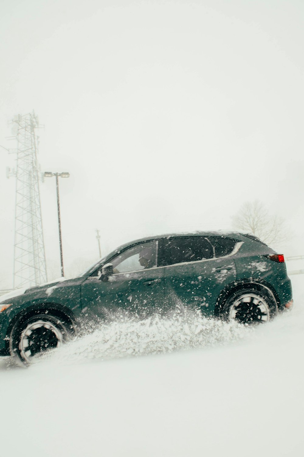 Um SUV verde dirigindo através de um campo coberto de neve