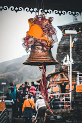 Close-up of a traditional temple bell and colorful marigold garlands at a peaceful village shrine.