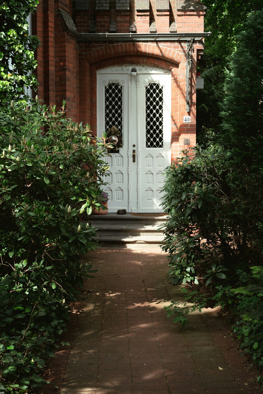 a brick house with a white door surrounded by greenery