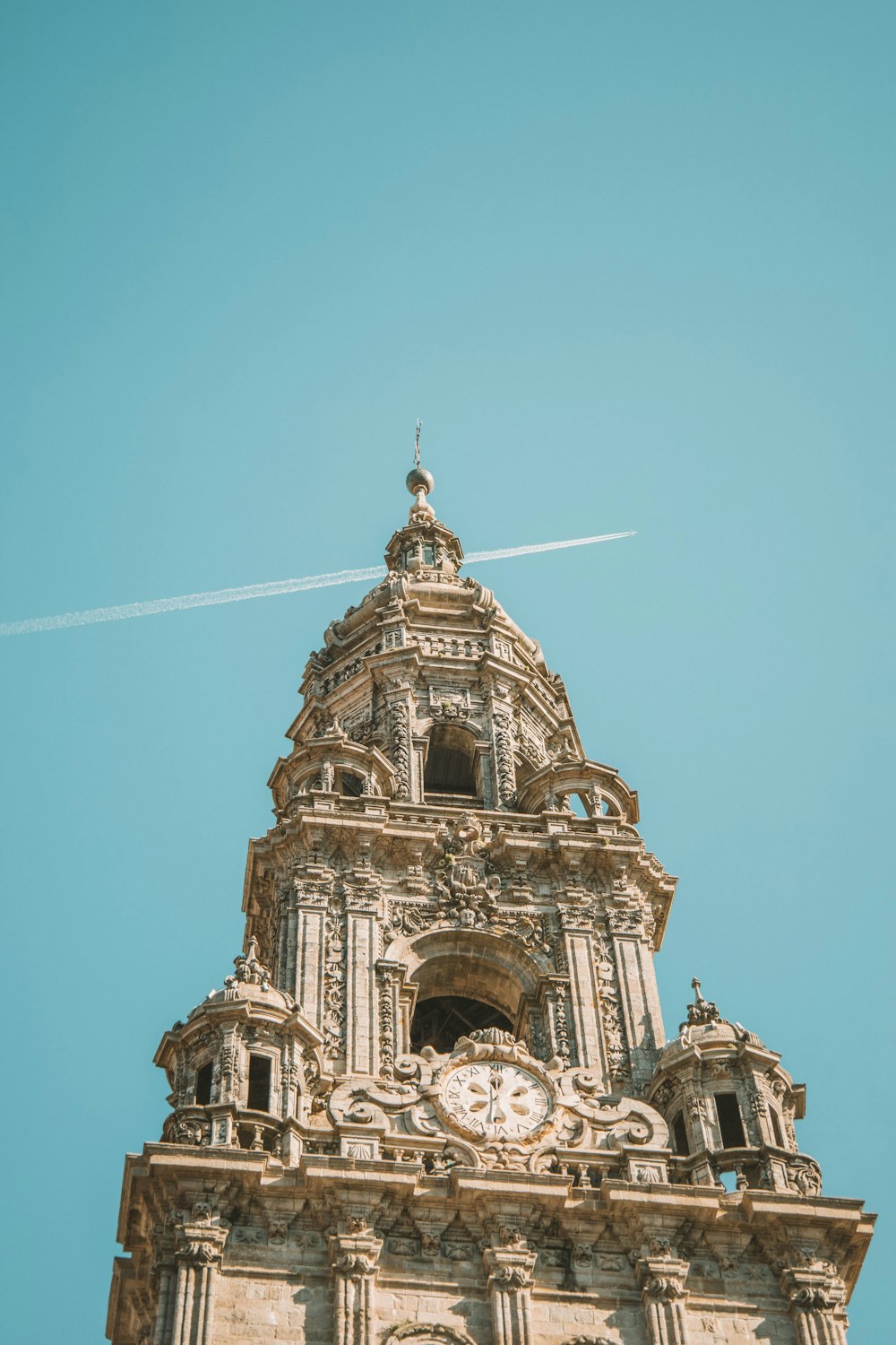 a tall tower with a clock and a plane in the sky