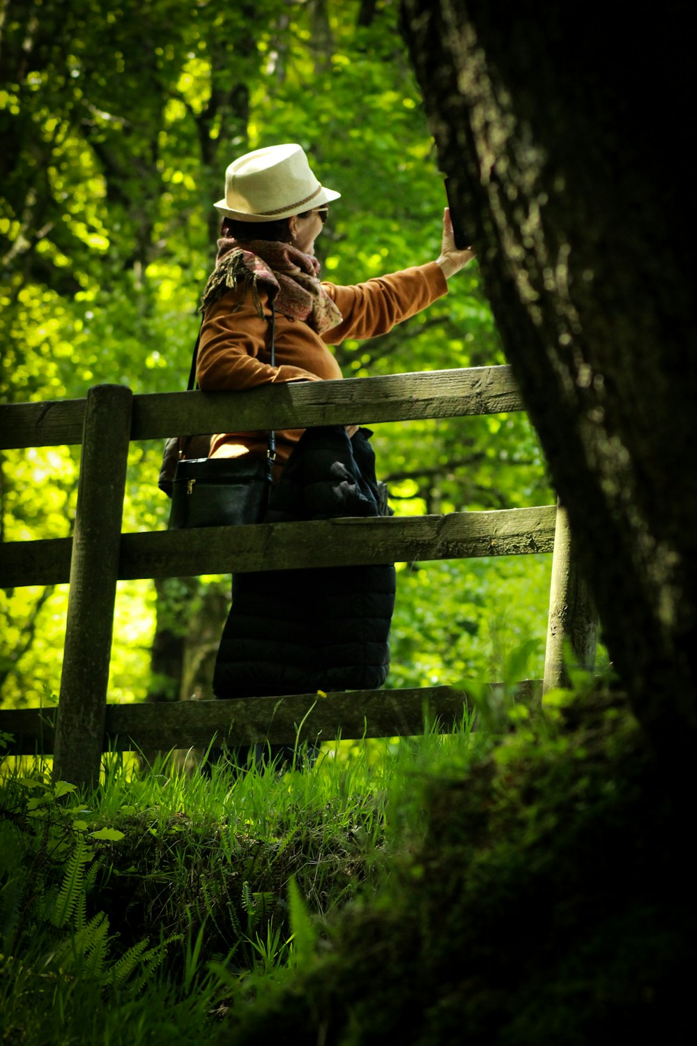 Une femme coiffée d’un chapeau est appuyée sur une clôture