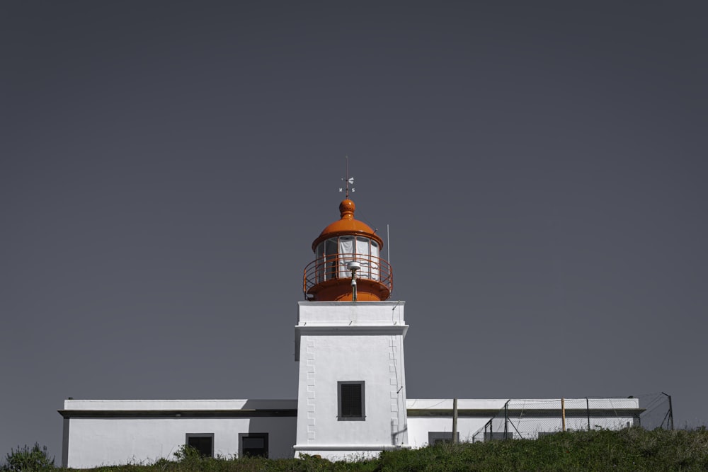 a white and orange lighthouse on top of a hill