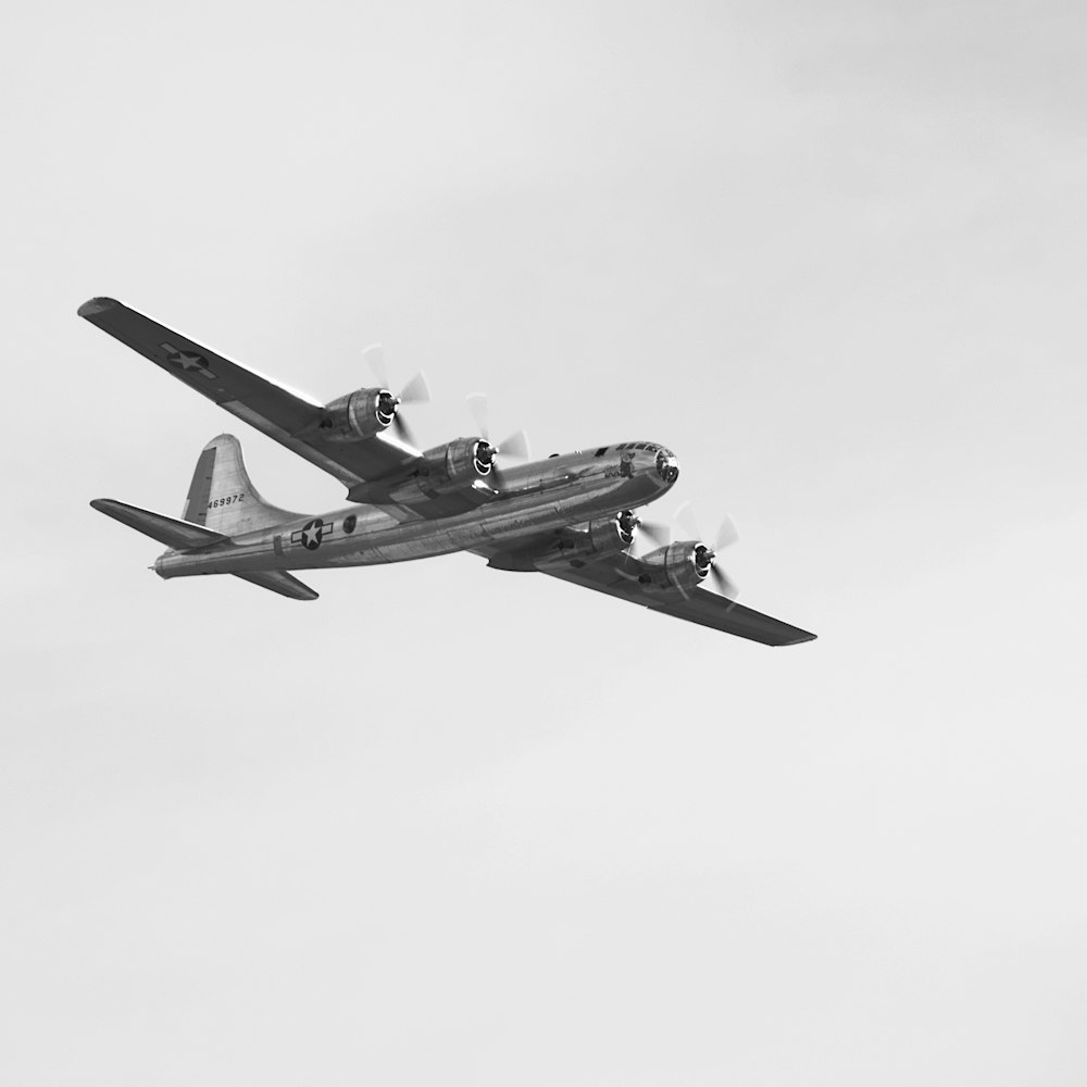 a black and white photo of a plane flying in the sky