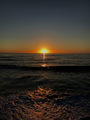 A serene sunset over a calm ocean, reflecting warm hues.