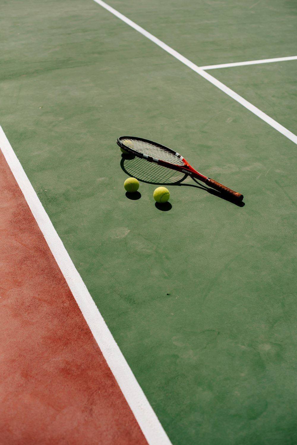 a tennis racket and two tennis balls on a tennis court