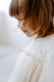 A serene portrait of a child wearing a soft beige cashmere sweater, captured in natural light with a warm ivory backdrop.