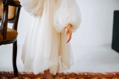 a woman in a white dress standing in front of a chair