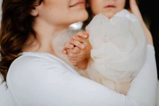 Close-up of a baby smiling while being gently held by a mother.