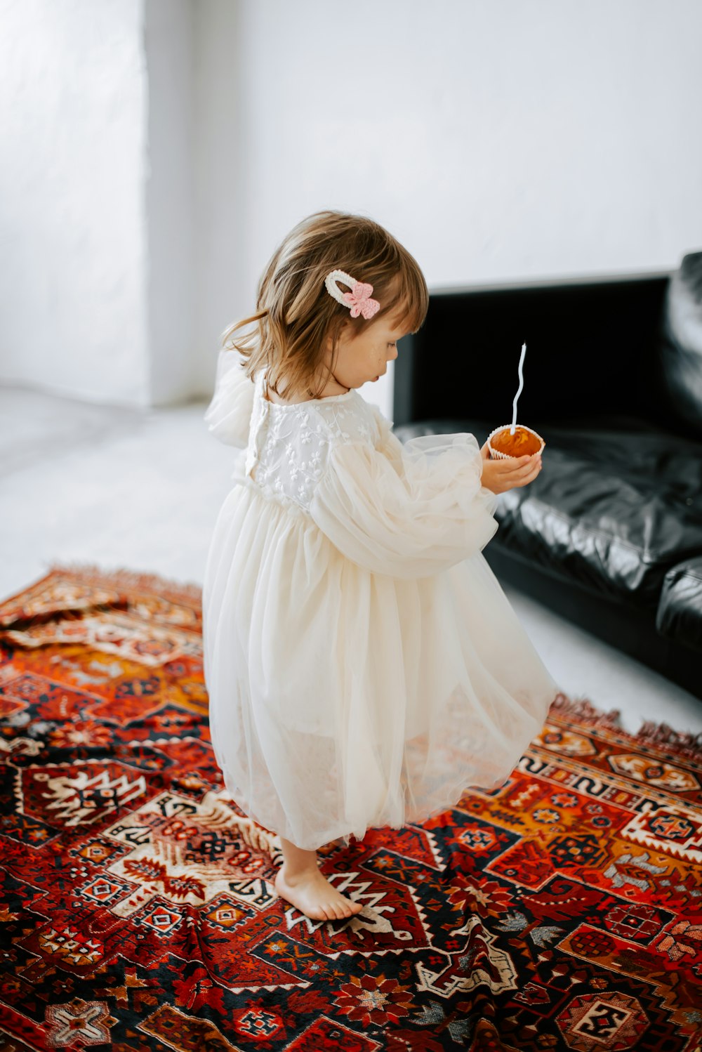 a little girl standing on a rug holding a bowl of food