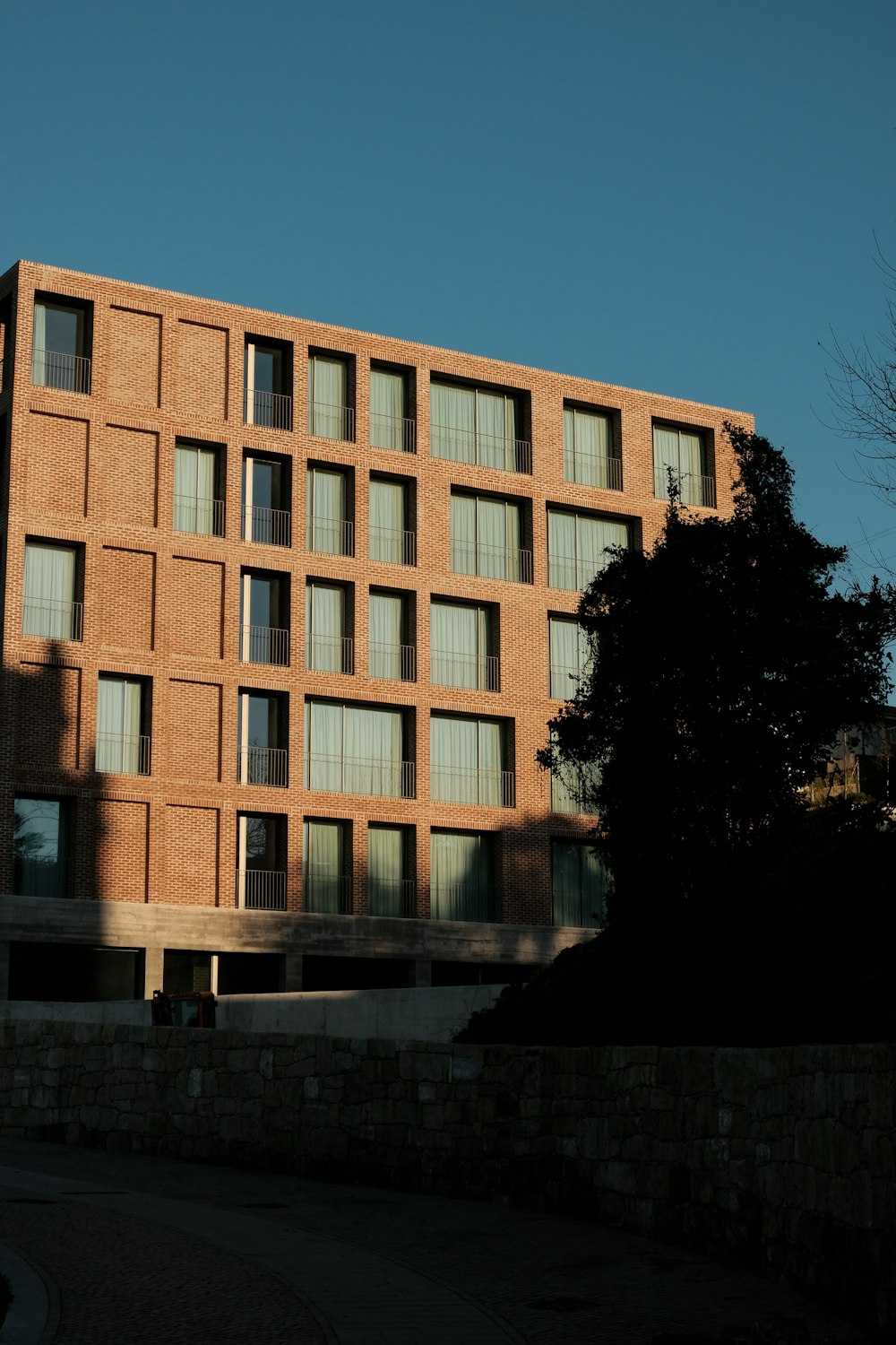 a tall brick building sitting next to a tree