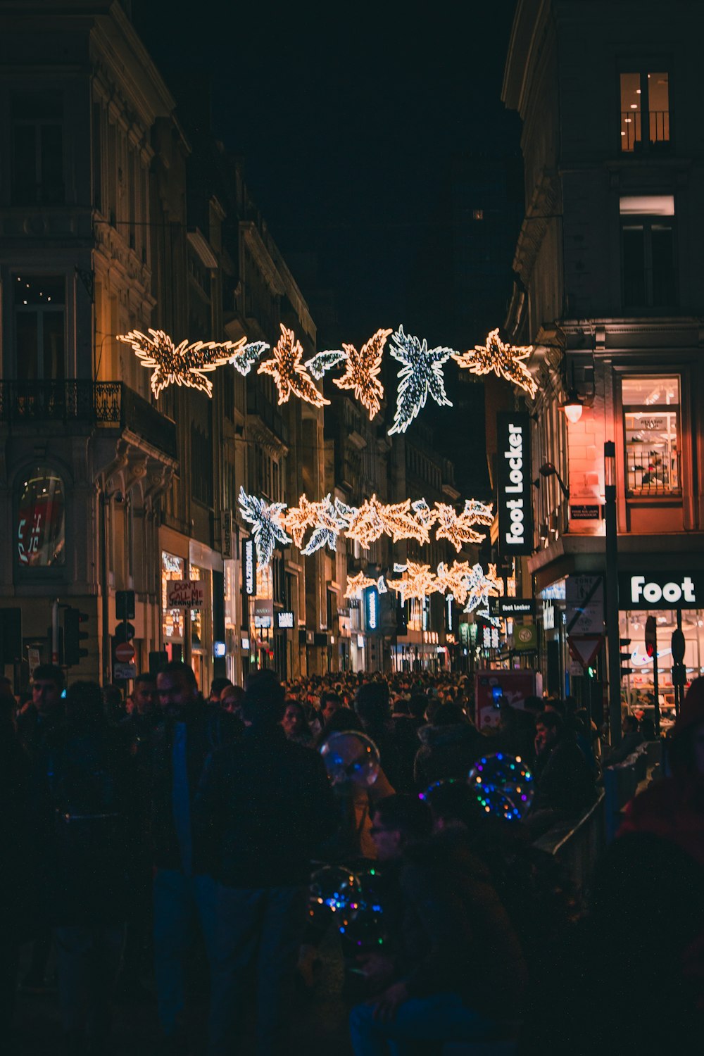 a crowd of people walking down a street at night