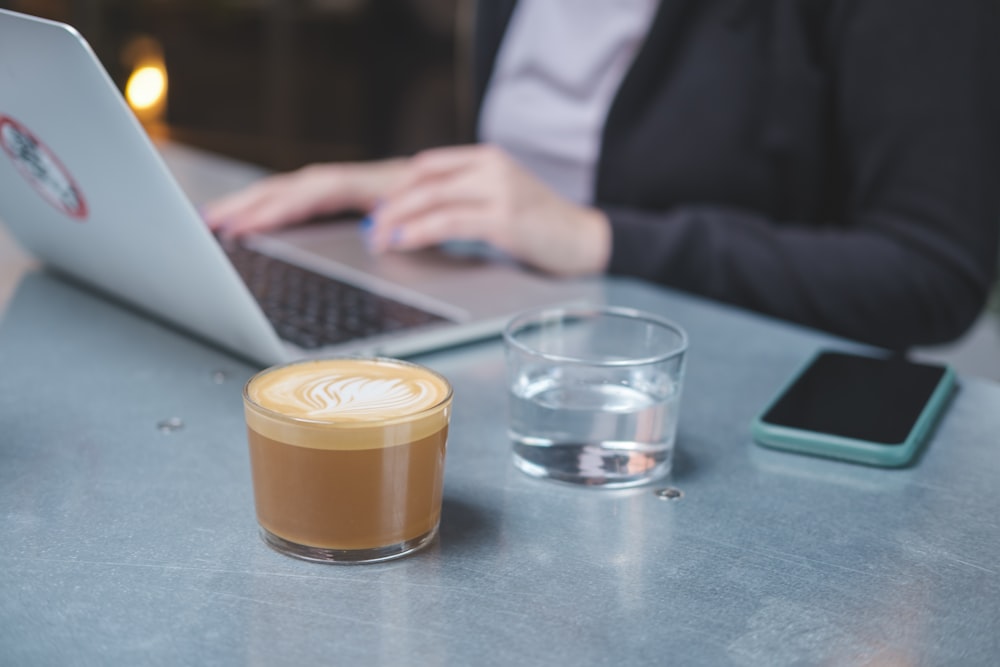 a woman sitting at a table with a laptop and a cup of coffee