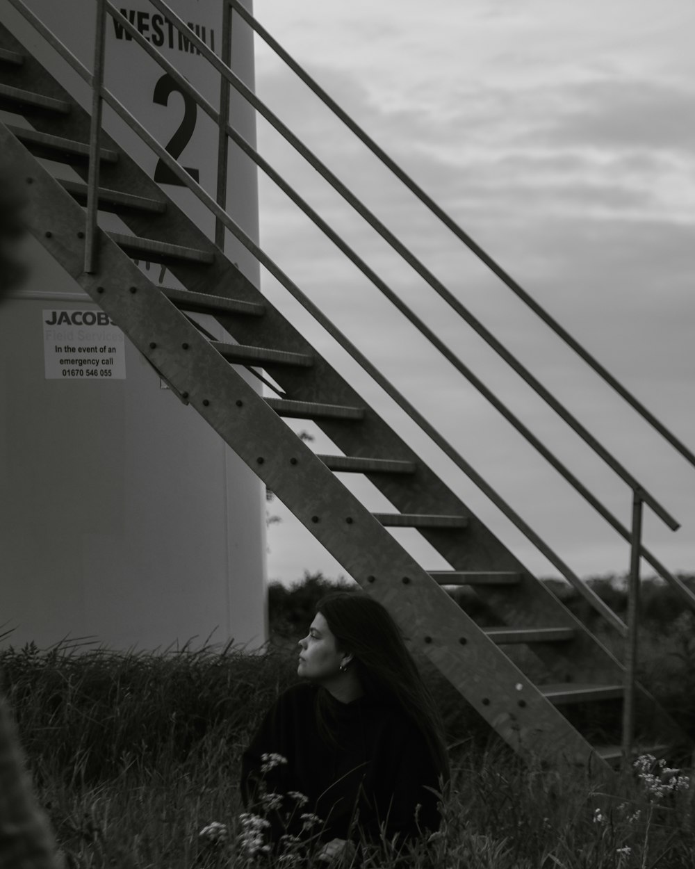 a woman sitting on the ground next to a stair case