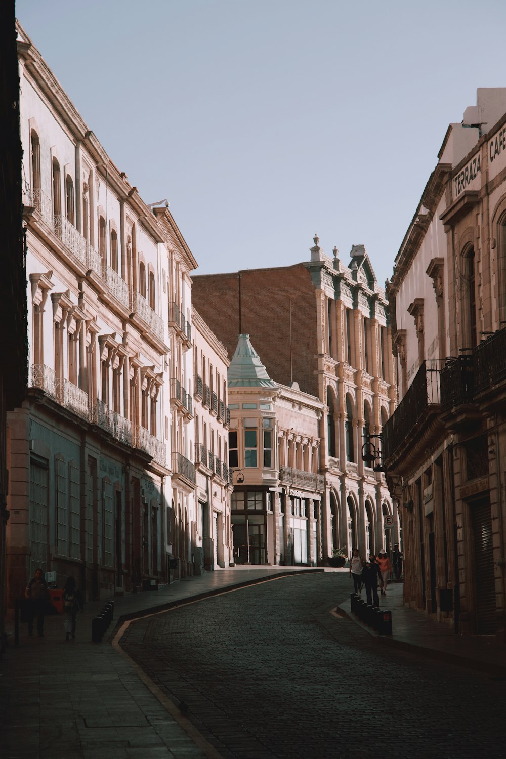 an empty street with a few people walking down it