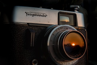 A close-up of a vintage film camera capturing a sunset over the ocean.