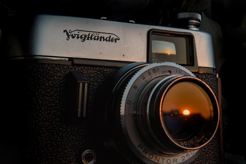 A close-up of a vintage film camera capturing a sunset over the ocean.
