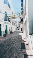 A sunlit cobblestone street in Lisbon with colorful buildings and hanging laundry.