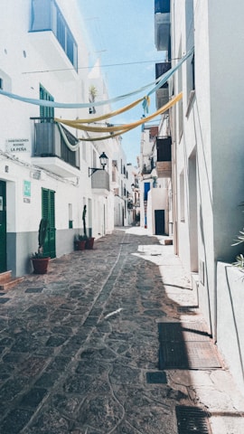 A sunlit cobblestone street in Lisbon with colorful buildings and hanging laundry.