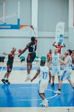 A dynamic basketball game moment with players in black and gold jerseys under bright arena lights.