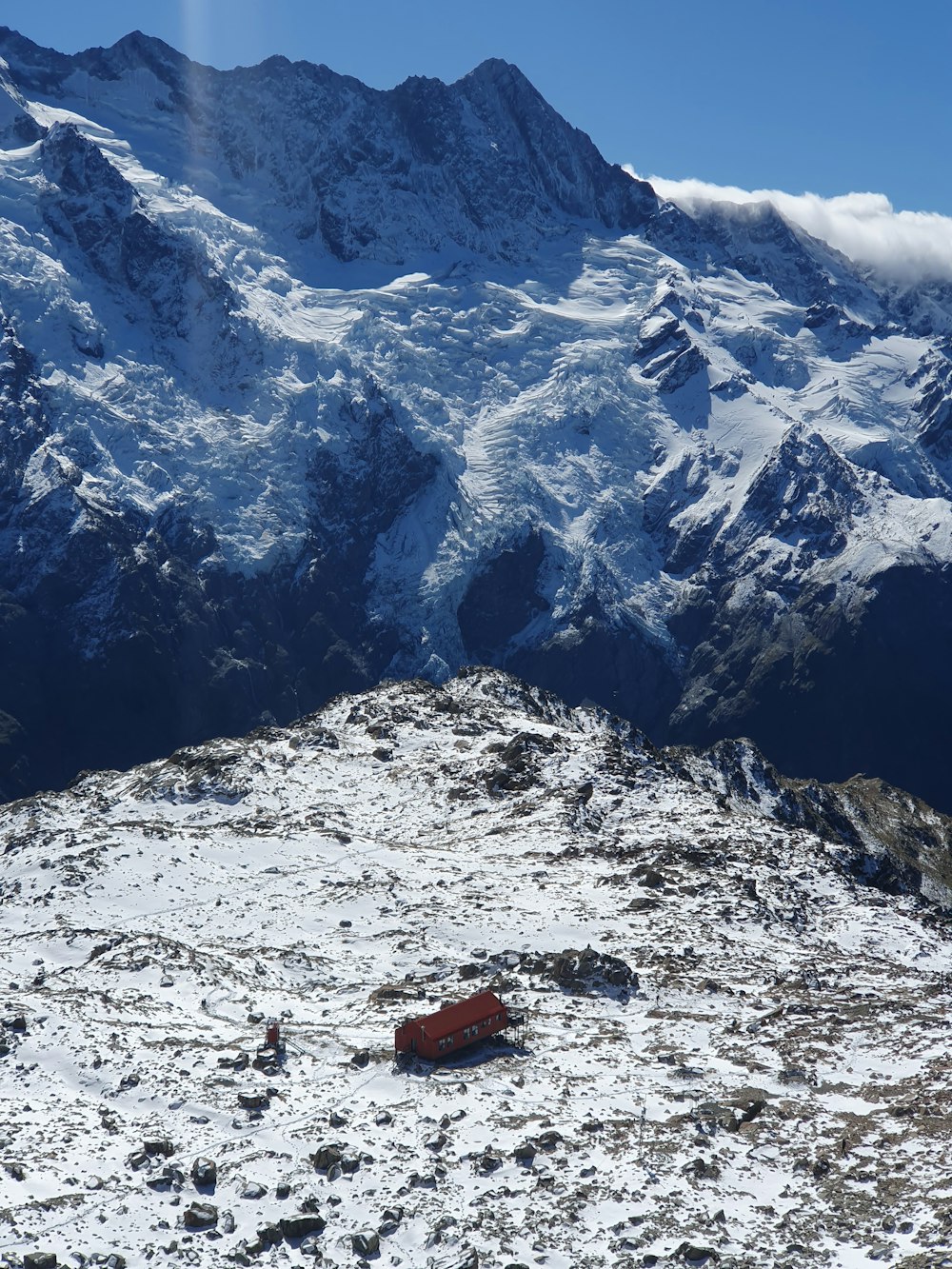 a snow covered mountain with a red car in the foreground