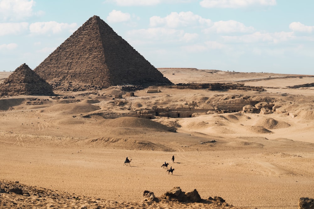 a group of people riding camels across a desert