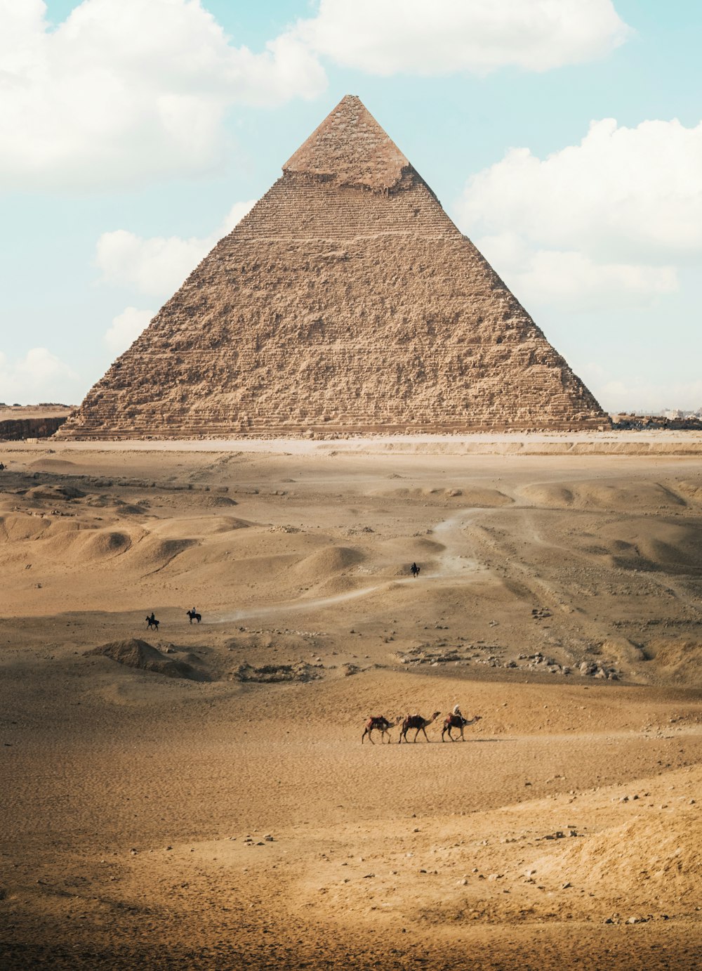 Eine Gruppe von Menschen reitet auf Pferden vor einer Pyramide