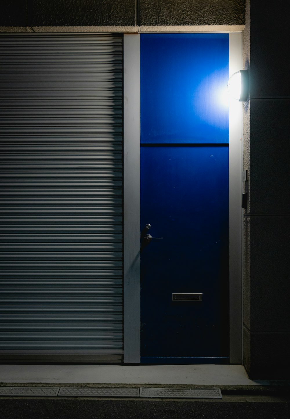 a blue door with a light on in front of a building