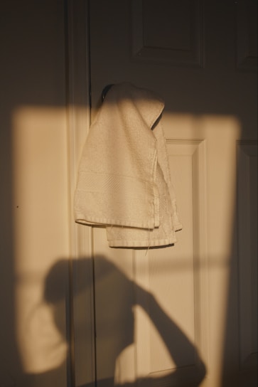A soft, fluffy towel draped over a wooden rack with sunlight streaming through a nearby window.