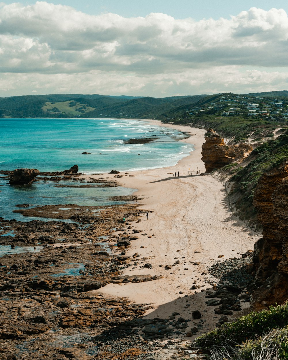 a sandy beach with a few people walking on it