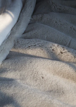 A close-up of a royal violet luxury blanket draped elegantly with soft gold accents catching the light.
