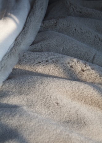 A gentle hand touching the plush texture of a limited edition pima cotton blanket under warm natural light.