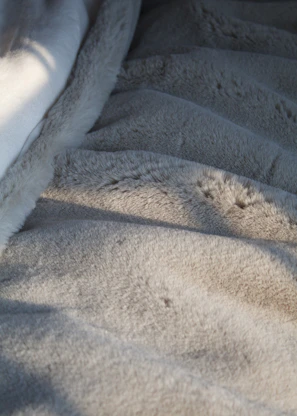 Close-up of a soft, textured blanket draped over a modern chair in natural light.