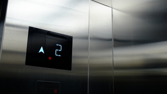 Close-up of a technician inspecting elevator control panel with tools.