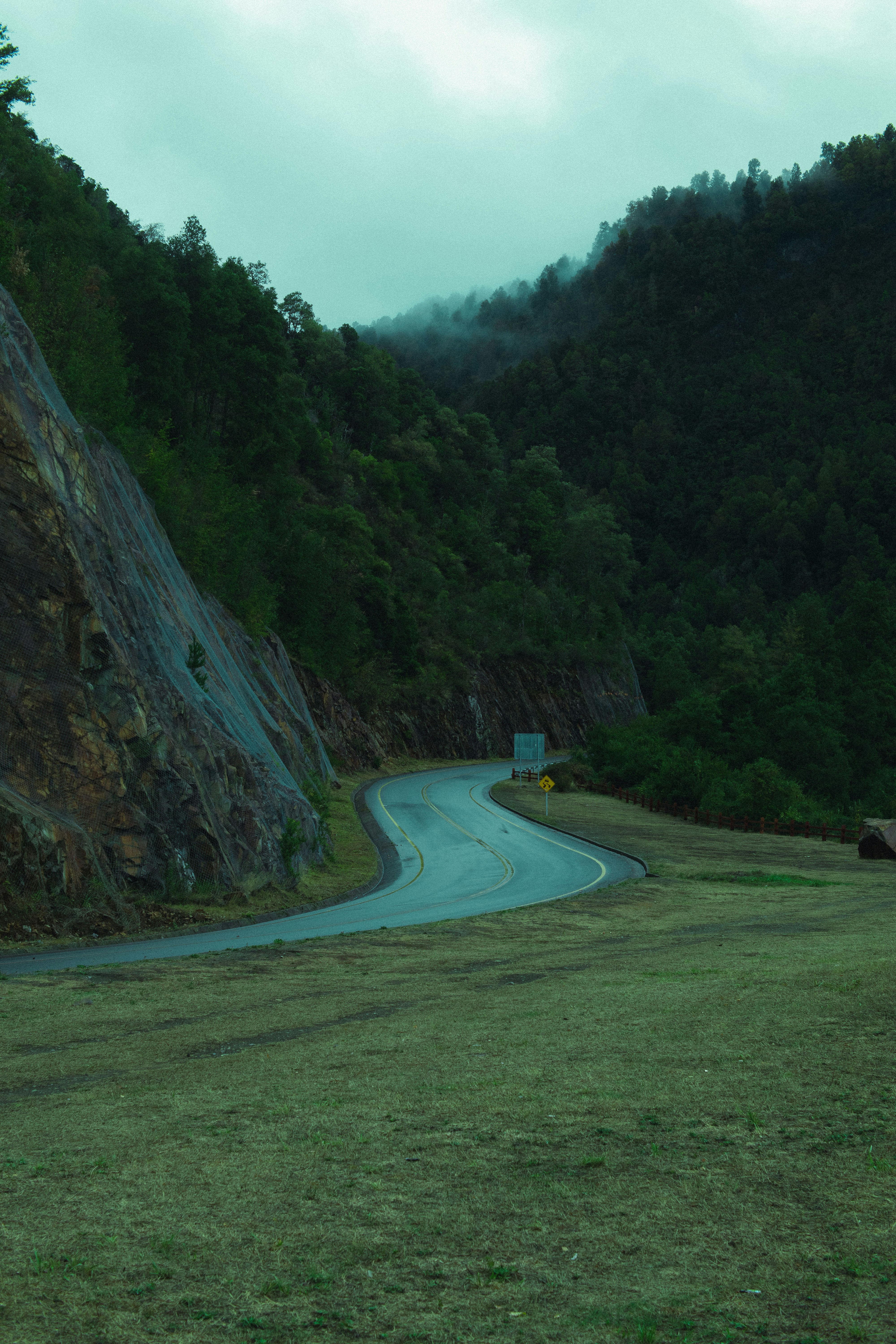 A curve in the road with a mountain in the background photo – Free ...