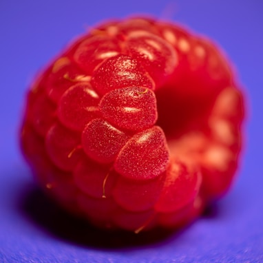 a close up of a raspberry on a blue background