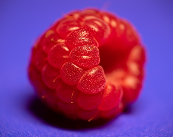 a close up of a raspberry on a blue background