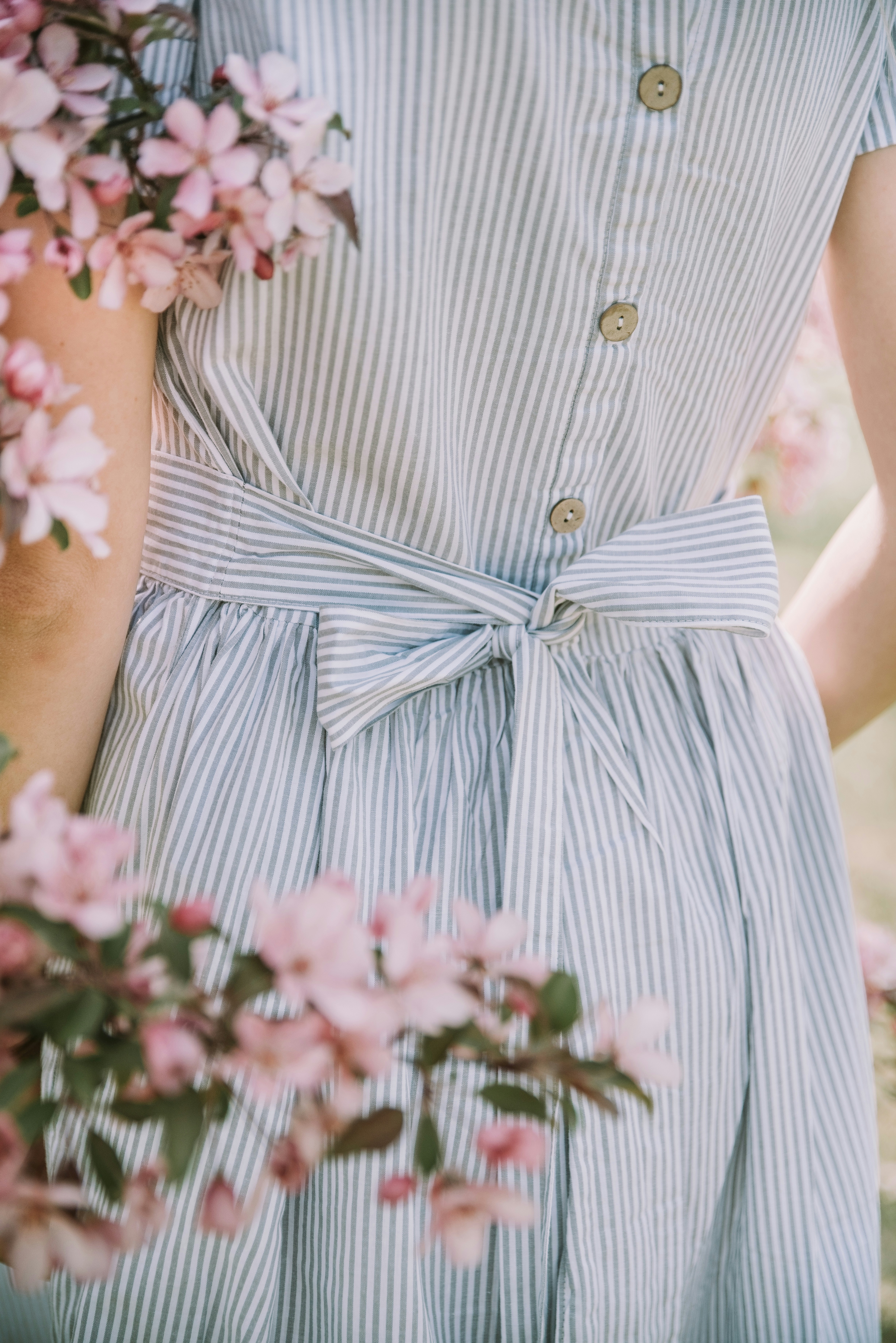 a woman in a striped dress holding a bunch of flowers