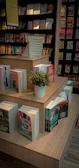 A multi-tier display rack showcasing books and small plants in a cozy nook.
