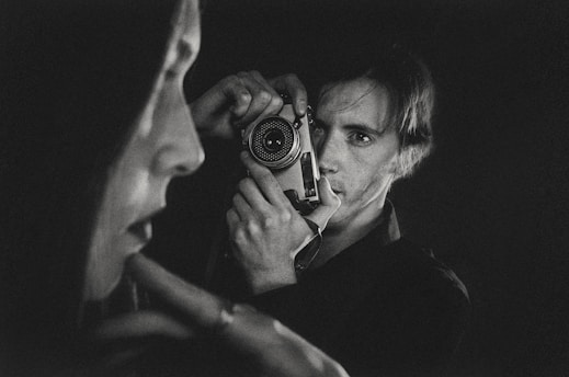 A serene black and white portrait of a thoughtful man holding a vintage camera, capturing the essence of timeless photography.