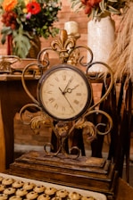 Close-up of an elegant old clock and vintage decorative items on a rustic wooden table.